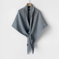 Detail of grey knitted wool shawl showing the thick fabric texture and leather logo tag - Light Gray