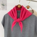 Dettaglio di una sciarpa a triangolo in maglia rosa acceso annodata su un gilet grigio - Rosa Rossa