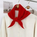 Dettaglio ravvicinato di una sciarpa a maglia rossa abbinata a un cardigan beige chiaro - Rosso