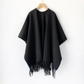 Detalle de chal negro tipo cachemira con flecos de borlas en una percha de madera - Negro