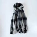Close-up of fluffy mohair scarf with black and grey plaid pattern and long tassel details - Black and White
