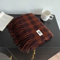 Detail of soft plaid cashmere-like scarf with long fringe and retro pattern on dark surface - Brown