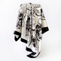 Macro shot of camellia print satin square scarf showing smooth silk texture and black border - Off-white