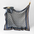Blue geometric floral pattern silk square scarf with deep blue border hanging on a wooden rack - Blue Rhyme Dream