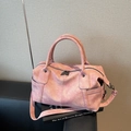 Vintage-Tragetasche in mattem Rosa mit Doppelgriffen und Schultergurt auf schwarzem Sofa - Rosa