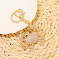 Close-up of golden crab keychain with sparkling rhinestones and metal lobster clasp - Pink