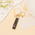 Dettaglio portachiavi dorato con cinturino in pelle e strass neri su piatto decorativo - Nero Paillettes