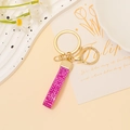 Dettaglio del portachiavi in pelle con strass rosa e chiusura dorata su vassoio decorativo - Strass Rosa