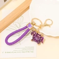 Detail of purple woven leather keychain with enamel pony charm and golden lobster clasp - Leather Rope Pendant / Purple