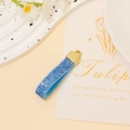 Close-up of blue rhinestone ribbon keychain with a polished gold alloy ring detail - Blue