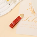 Close-up of red rhinestone encrusted U-shaped pendant charm with gold metal clasp - Red