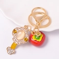 Detailopname van gouden sleutelhanger met rode emaille persimmon en glanzende steentjes - Kaki Rood