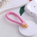 Dettaglio ravvicinato di un portachiavi in pelle intrecciata rosa con ciondolo a cuore - Ciondolo a Cuore Rosa in Corda Intrecciata