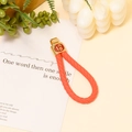 Dettaglio del portachiavi intrecciato arancione con ciondolo dorato con carattere Fu - Corda Intrecciata Rossa (Carattere Fu)