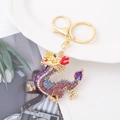 Dettaglio di un portachiavi a forma di drago dorato con strass colorati brillanti e vivaci - Dragone Dorato con Strass Viola