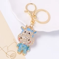 Dettaglio macro del portachiavi bue cartone con strass blu e chiusura dorata - Pendaglio Mucca Cartoon Strass (Blu) / Celeste