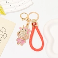 Dettaglio del portachiavi a mucca con strass e cinturino in pelle rossa intrecciata - Pendaglio Mucca Strass + Corda Intrecciata Rosa