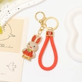Close-up of golden zodiac rabbit keychain with red rhinestones and Fu symbol charm - Red Rope + Red-White Rhinestone Rabbit