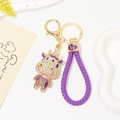 Dettaglio portachiavi a mucca dorata con cristalli viola e cinturino intrecciato - Pendaglio Mucca Strass + Corda Intrecciata Viola
