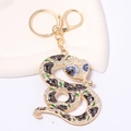 Macro-opname van een gouden slang sleutelhanger met strass en zwarte emaille rozen - Zwarte Roos Stijl