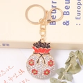 Détail du porte-clés sac de fortune doré avec strass blancs et motifs de fleurs rouges - Style Fleur Rouge