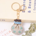 Détail macro du porte-clés sac de fortune avec fleurs en émail bleu et strass brillants - Style fleur bleue