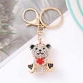 Sparkling teddy bear keychain with white and red rhinestones on a pink background - Red