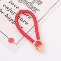 Detail van de rode gevlochten touwsleutelhanger met gouden hartbedeltje op een kaartje - Rood