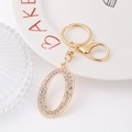 Macro shot of gold tone letter O keychain with sparkling rhinestones and lobster clasp - Number 0