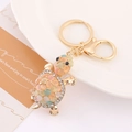 Golden turtle keychain with opal shell and sparkling rhinestones on a white plate - Turtle 31 (Inlaid Colored Stones)