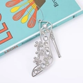 Elegant silver high heel shoe pendant necklace with sparkling diamonds on a blue book - High Heel