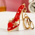 Vista macro del portachiavi a scarpa rossa con rose e strass brillanti su metallo dorato - Rosso