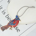 Detail van een gouden vogelhanger met rood en blauw email en glanzende ingelegde strasstenen - Veelkleurige Emaillen Vogel / Rood en blauw tweekleurig