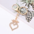Detail of a golden heart crown keychain with sparkling rhinestones on a white background - White