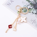 Detailed view of a gold clover keychain with red key, white flower, and pearl charms - Red