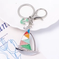 Detailed macro view of a colorful enamel sailboat keychain with a small green anchor charm - Silver Sailing Boat Style