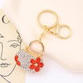 Detalle de llavero de bolso con flores y diamantes blancos en aleación dorada - Naranja
