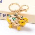 Detailed macro of golden elephant keychain with yellow enamel and green gemstones - Yellow