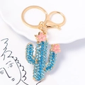 Dettaglio del portachiavi a forma di cactus dorato con strass blu e fiori smaltati rosa - Stile Blu
