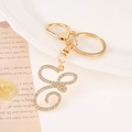 Macro view of gold-plated letter S keychain with sparkling white rhinestones on white plate - Letter E(E) / Gold