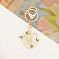 Close-up of golden heart keychain with letter M, pink enamel flower and leaf detail - Letter M Style