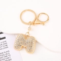 Macro view of gold crystal letter M keychain with sparkling rhinestones and lobster clasp - Letter M