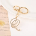 Macro detail of gold-plated letter Q keychain with sparkling rhinestones and lobster clasp - Letter Q(Q) / Gold