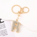Detail shot of golden letter R keychain with sparkling rhinestones and lobster clasp - Letter R