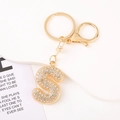 Detail of gold letter S keychain with crystal rhinestones on a white pedestal display - Letter S