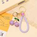 Portachiavi ciliegia glitterato con foglia di strass e cordino viola su sfondo caldo - Ciliegia Glitter con Cordino Viola / Fucsia