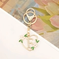Detailed close-up of golden heart-shaped keychain with crystal-studded letter E and pink flowers - Letter F Style
