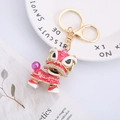 Chinese lion dance keychain in red and gold finish with rhinestones and pink beads - Red & White