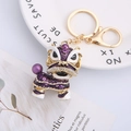 Purple Chinese lion dance keychain with rhinestones and pearls on a white plate - Purple