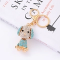 Primer plano detallado de un llavero de caniche dorado con cristales azules y blancos - Azul lago
